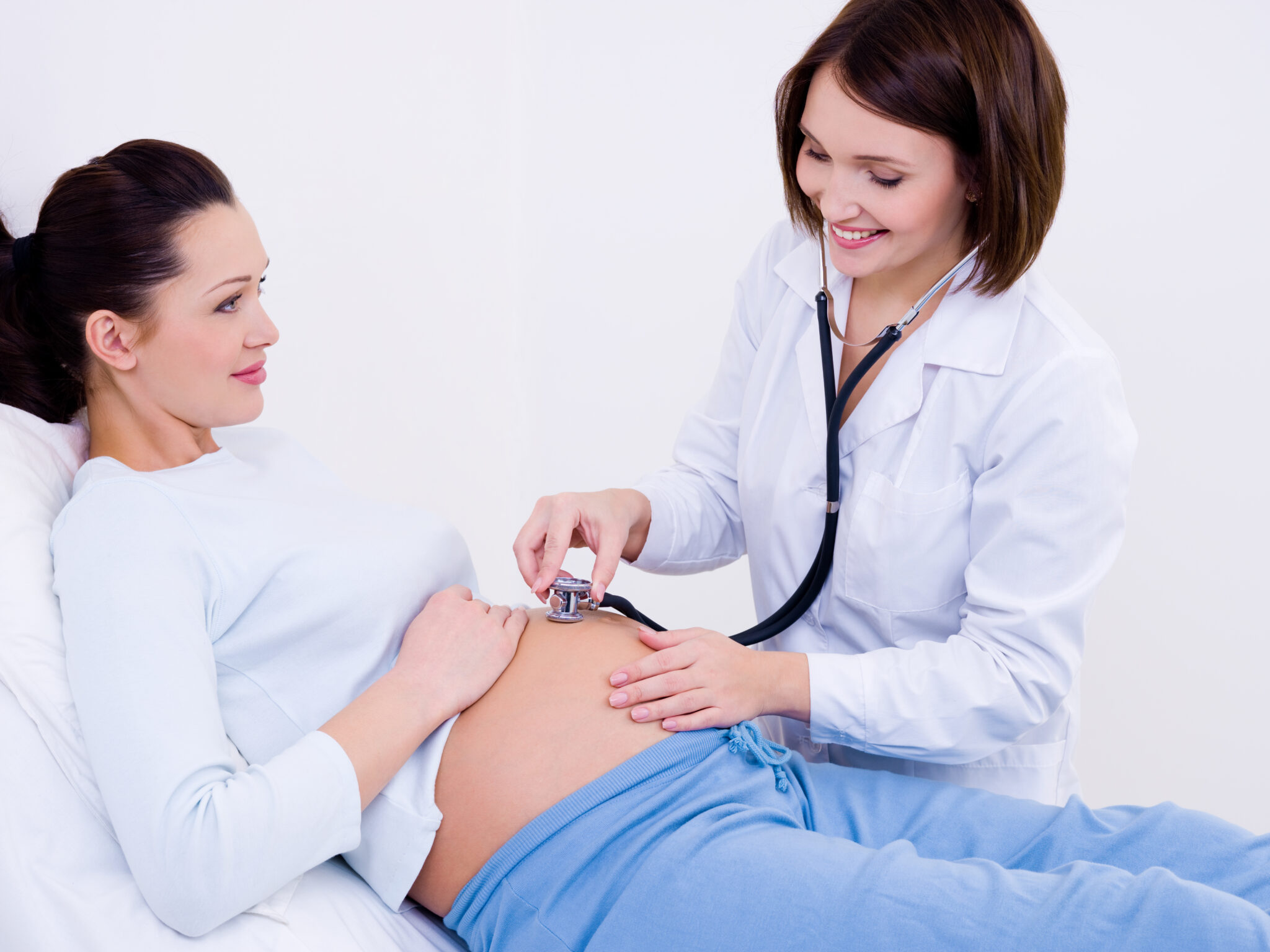 Doctor listens the tummy of a pregnant woman