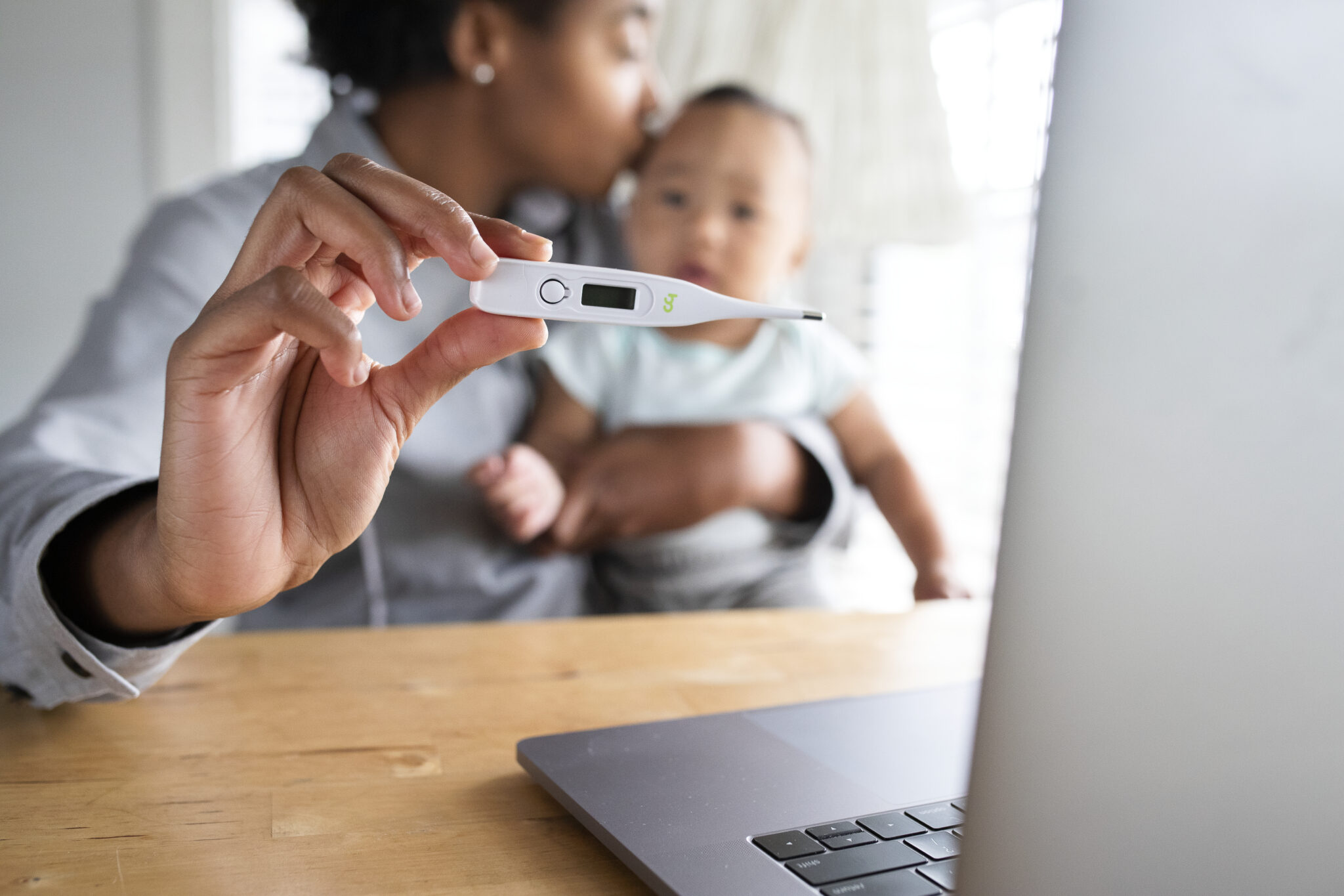 African American mom showing baby’s fever to doctor through telemedicine call