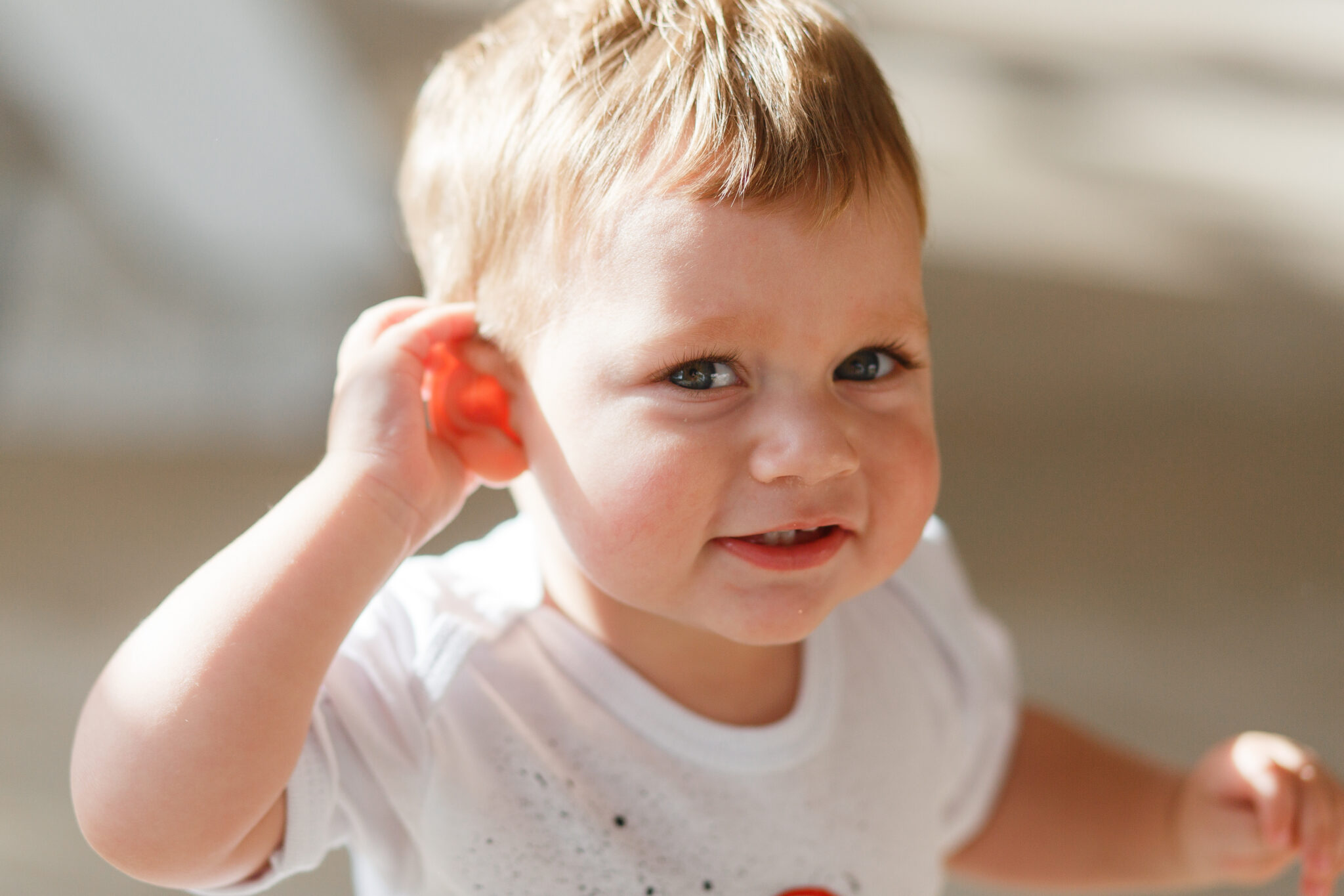 baby boy listens to put a hand to his ear.