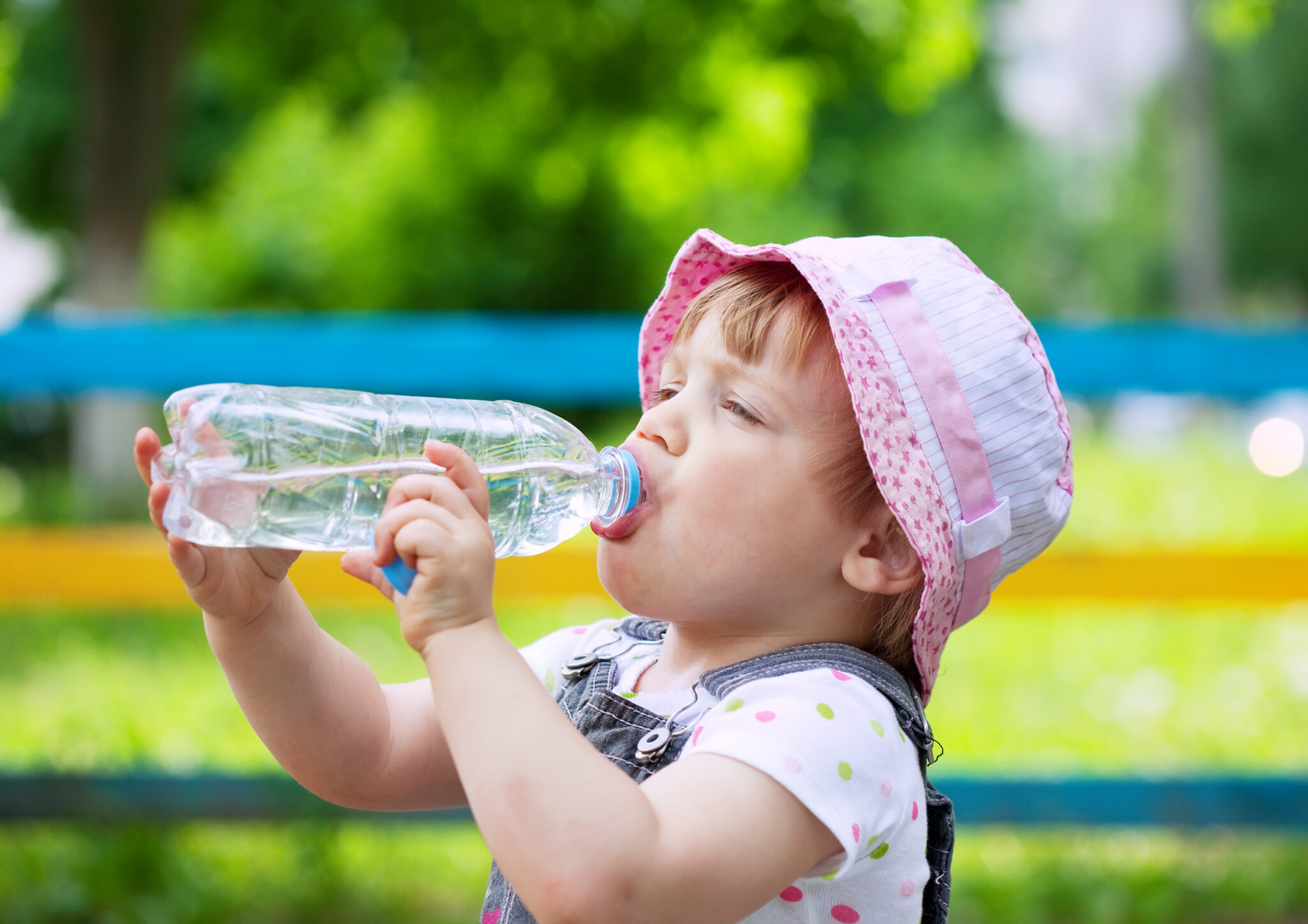 two-year child drinks from plastic bottle in park